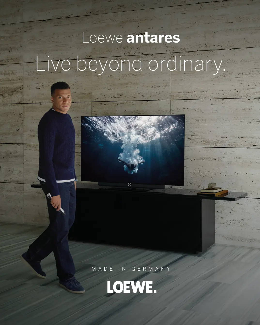 LOEWE antares OLED-Fernseher auf einem dunklen Lowboard vor einer Betonwand